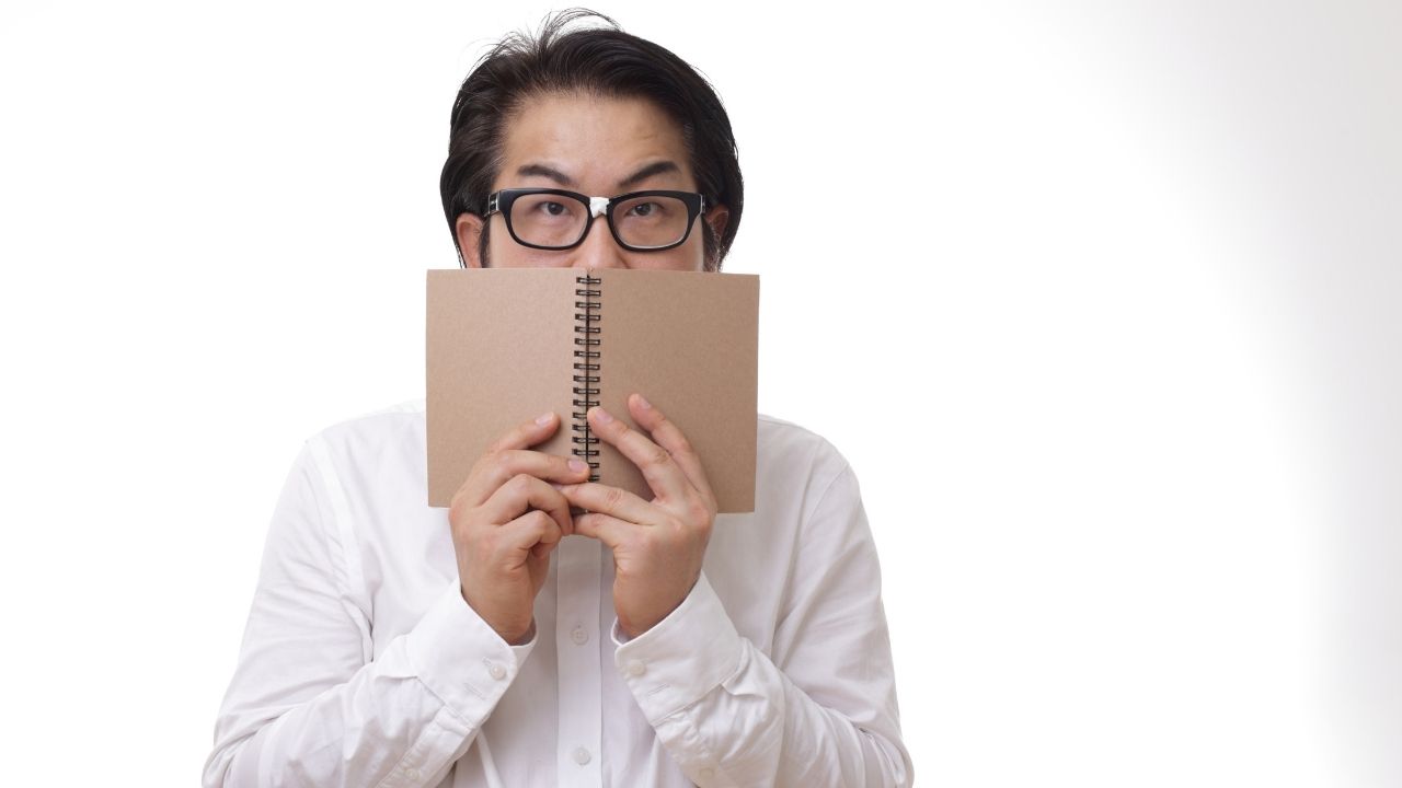 man hiding behind book